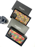 Two Chanel phone cases with floral designs in black boxes on a white background.